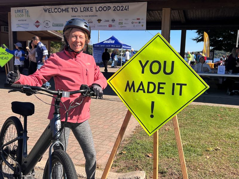 A bicyclist stands besides a sign that says 