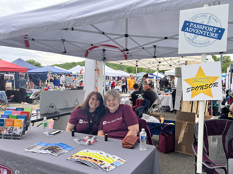 Two people sit behind a table at a branded stand