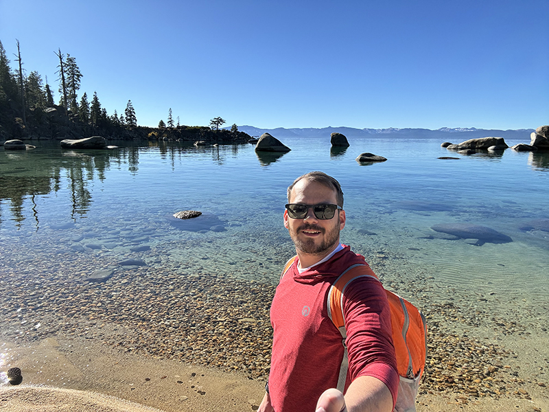 Kyle, who is attending the NALMS Conference, stands at the edge of Lake Tahoe, taking a selfie