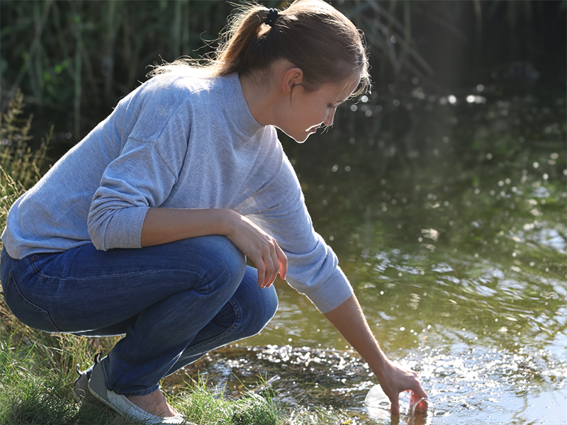 A woman takes a water sample.